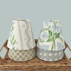 two lampshades sitting on top of a wicker basket next to each other