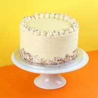 a white cake with sprinkles sitting on top of an orange table