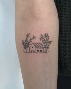 a woman's arm with a small house and trees tattoo on the left forearm