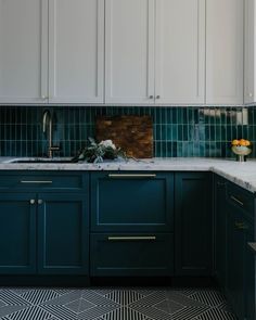 a kitchen with white cabinets and green tile backsplash