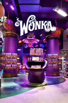 the entrance to wonka's is lit up with purple lights and balloons in the background