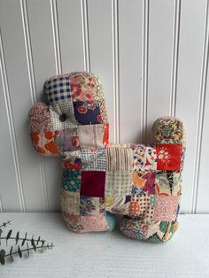 a teddy bear made out of patchwork fabric sitting on top of a white table