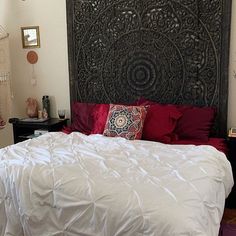 a bed with white sheets and red pillows