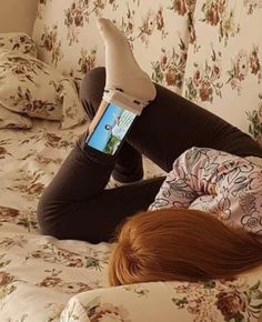 a woman laying on top of a bed holding a cell phone