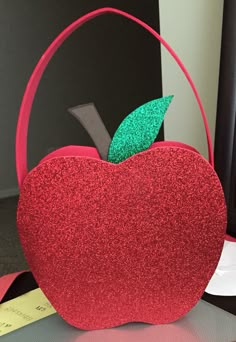 an apple shaped purse sitting on top of a desk