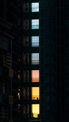 the sun is setting in between two tall buildings with balconies on each floor