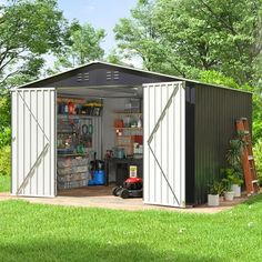 a shed with the doors open and tools in it on top of some grass next to trees