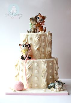 a three tiered cake with figurines on top and cats sitting on top