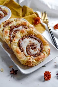 two cinnamon rolls on a plate with forks