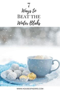 a blue cup and saucer filled with white chocolate balls on top of snow covered ground