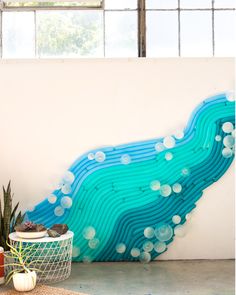 an abstract painting on the wall next to a basket and potted plant in front of it