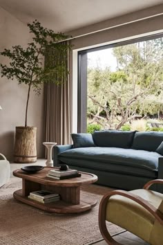 a living room filled with furniture and a large window overlooking the trees in the distance