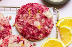 the cookies are covered in cranberry and orange zest icing next to some lemon wedges