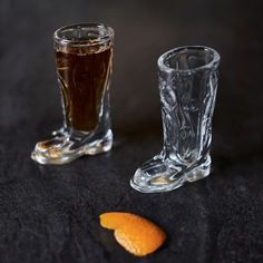 an orange and a glass on a black table with one half eaten orange next to it