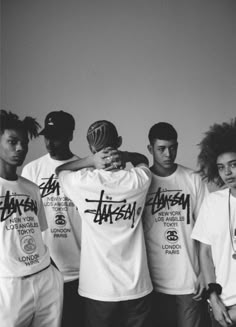 a group of young men standing next to each other in front of a white wall