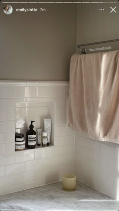 a bathroom with white tile and towels hanging on the wall