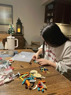 a woman sitting at a table with lots of legos on the table and toys in front of her