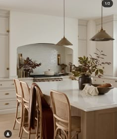 a kitchen with white cabinets and an island in the middle, surrounded by wooden chairs