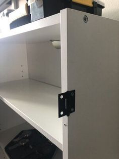 a white shelf with some black and yellow items on it's shelves in a room