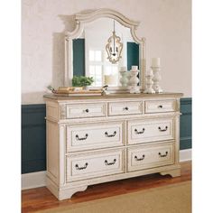 a white dresser with a mirror on top of it next to a rug and wall