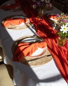 the table is set with orange napkins and place settings