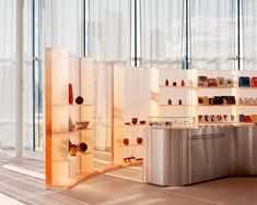 a room filled with lots of books and shelves next to tall glass windows on the wall