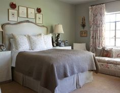 a bed sitting in a bedroom next to a window covered in white sheets and pillows