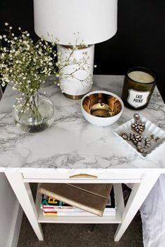 a white table topped with a lamp next to a vase filled with flowers and other items