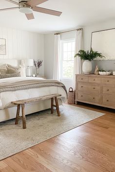 a bed room with a neatly made bed and a wooden dresser next to a window