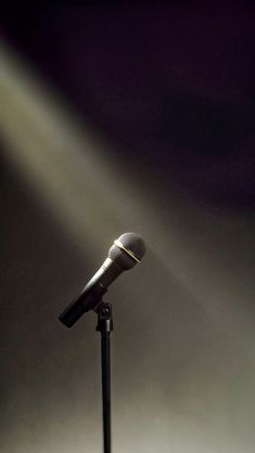 a microphone on a stand in front of a light from the spotlight shining down on it