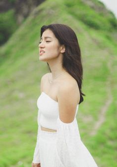 a woman standing in front of a grassy hill