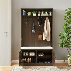 a coat rack with shoes and coats hanging on it next to a potted plant