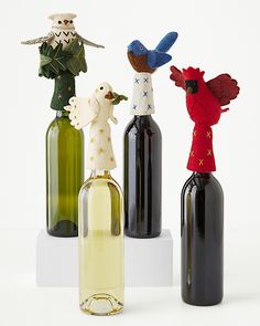 three wine bottles with figurines in them sitting next to each other on a white surface