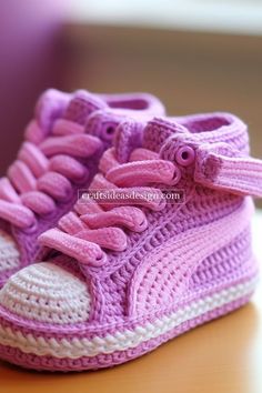 a crocheted pink and white sneaker with laces on the top is sitting on a table