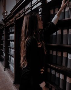 a woman standing in front of a bookshelf filled with lots of shelves full of books