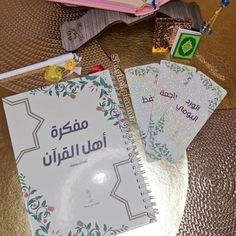 three books are sitting on a table next to some pens and pencils with arabic writing