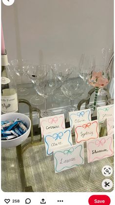 two wine glasses and some candy are on the table with place cards in front of them