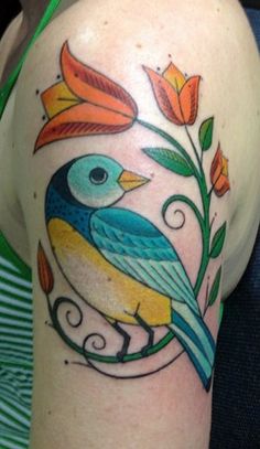 a colorful bird on the arm with flowers and leaves around it's back side