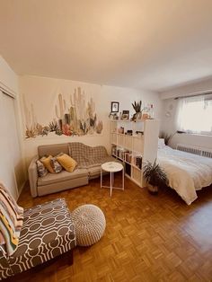 a living room filled with furniture next to a bed and a wooden floor covered in pillows