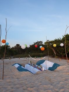 an outdoor party set up on the beach with balloons and streamers in the air