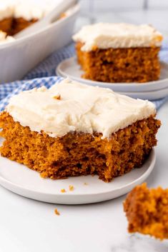 a piece of carrot cake with cream cheese frosting on a white plate next to another slice