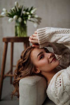 a woman is sitting on a couch with her arms behind her head and looking at the camera