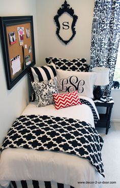 a black and white bedroom with monogrammed bedding, framed pictures, and decorative accessories