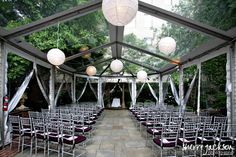 an outdoor wedding venue set up with purple chairs and white lanterns hanging from the ceiling