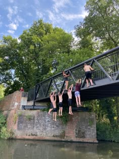 four people jumping off a bridge into the water