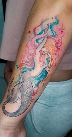 a woman's arm with a colorful mermaid tattoo on her left forearm and hand