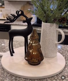 two ceramic deer figurines sitting on top of a counter next to a coffee cup