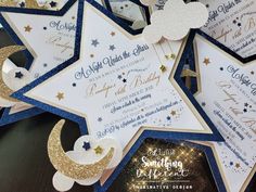 the stars and moon are on top of the blue and white wedding stationery with gold glitter