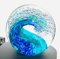 a glass ball with blue water and bubbles in the shape of a wave on it