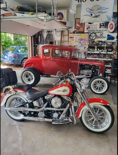 a red motorcycle parked next to a red car in a garage with other vehicles behind it